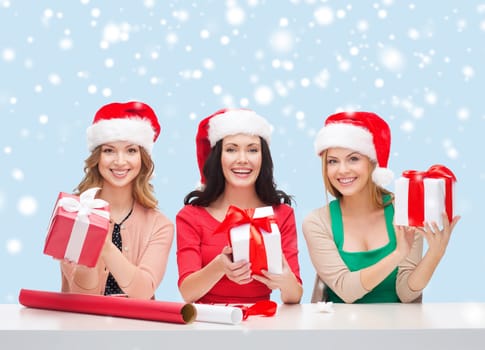 christmas, x-mas, winter, happiness concept - three smiling women in santa helper hats with gift boxes