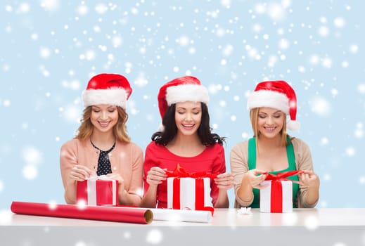 christmas, x-mas, winter, happiness concept - three smiling women in santa helper hats with gift boxes