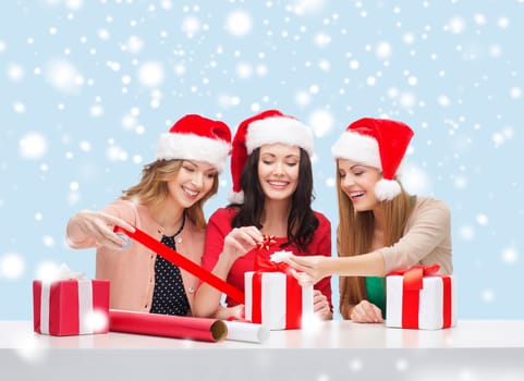 christmas, x-mas, winter, happiness concept - three smiling women in santa helper hats with gift boxes