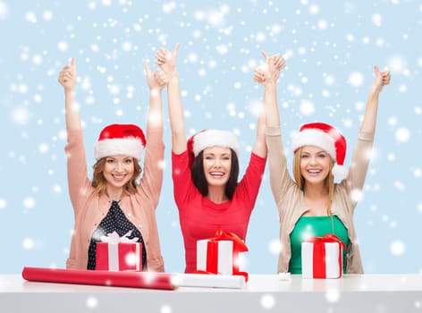 christmas, x-mas, winter, happiness concept - three smiling women in santa helper hats with gift boxes