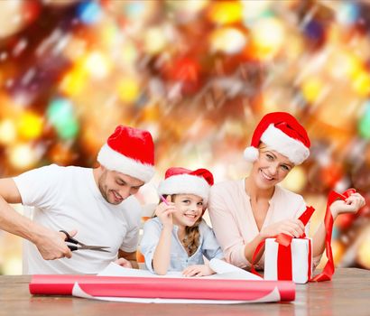 christmas, x-mas, winter,family, happiness and people concept - smiling family in santa helper hats with gift box