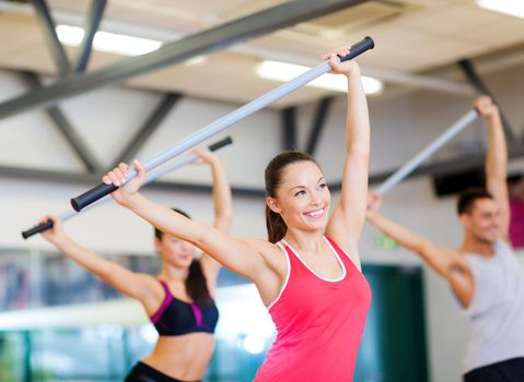 fitness, sport, training, gym and lifestyle concept - group of smiling people working out with barbells in the gym