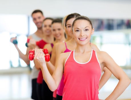 fitness, sport, training, gym and lifestyle concept - group of smiling people lifting dumbbells in the gym