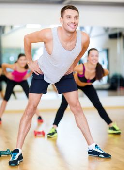 fitness, sport, training, gym and lifestyle concept - smiling male trainer working out in the gym