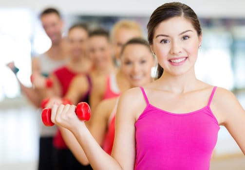 fitness, sport, training, gym and lifestyle concept - group of smiling people lifting dumbbells in the gym