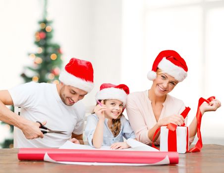 christmas, x-mas, winter,family, happiness and people concept - smiling family in santa helper hats with gift box