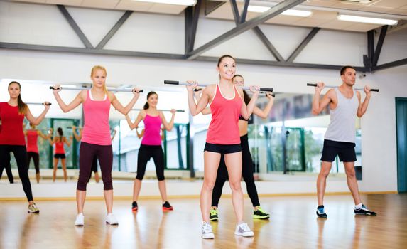 fitness, sport, training, gym and lifestyle concept - group of smiling people working out with barbells in the gym