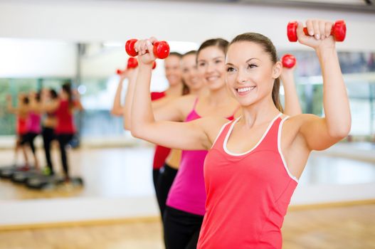 fitness, sport, training, gym and lifestyle concept - group of smiling people working out with dumbbells in the gym