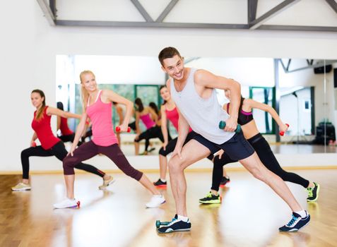 fitness, sport, training, gym and lifestyle concept - group of smiling people working out with dumbbells in the gym