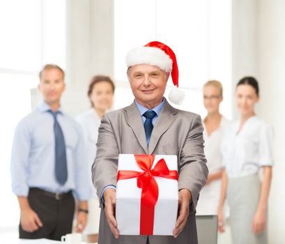 business, christmas, xmas, happiness concept - smiling old man in suit and santa helper hat with gift