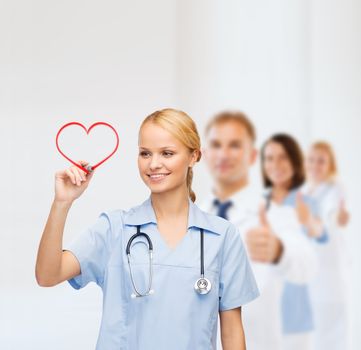 healthcare, medical and technology - young doctor or nurse drawing red heart