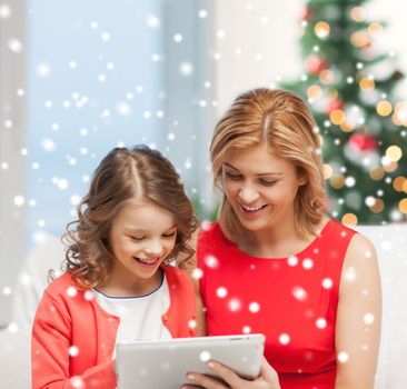 christmas, x-mas, winter, happiness, modern technology concept - mother and daughter with tablet pc