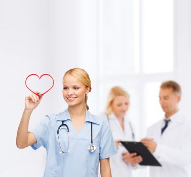healthcare, medical and technology - young doctor or nurse drawing red heart
