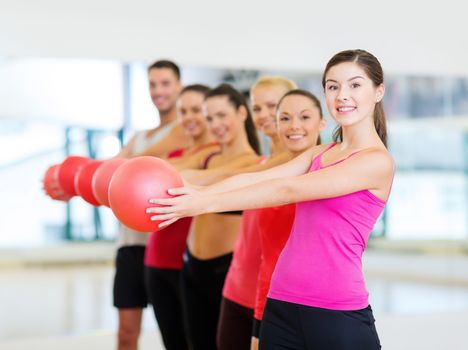 fitness, sport, training, gym and lifestyle concept - group of smiling people working out with stability balls in the gym