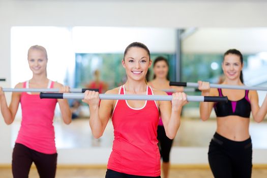 fitness, sport, training, gym and lifestyle concept - group of smiling people working out with barbells in the gym