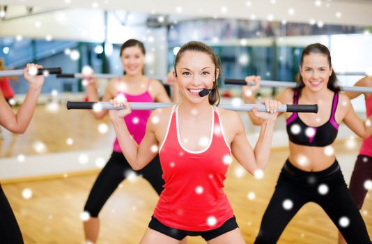 fitness, sport, training, gym and lifestyle concept - smiling trainer in front of the group of people working out with barbells in the gym