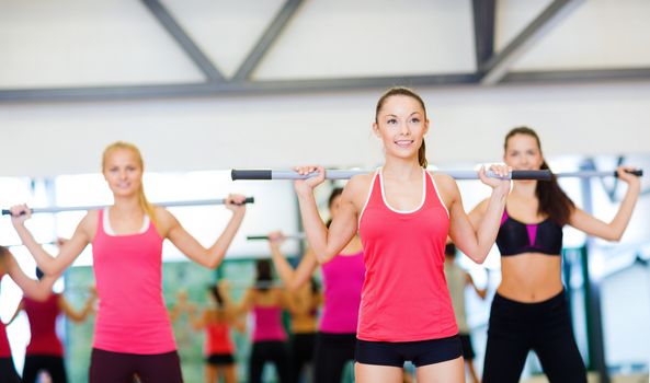 fitness, sport, training, gym and lifestyle concept - group of smiling people working out with barbells in the gym