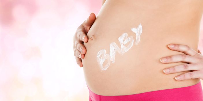 pregnancy, maternity and health concept - belly of a pregnant woman with cream