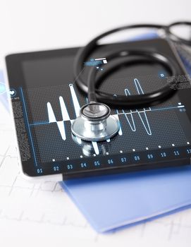 healthcare, medicine and technology concept - tablet pc, stethoscope and electrocardiogram
