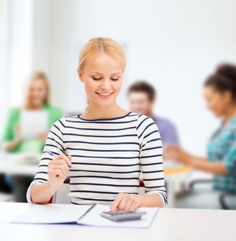 education, school and business concept - smiling woman with notebook and calculator studying in college