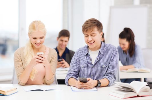 education and technology concept - group of students looking into smartphone at school