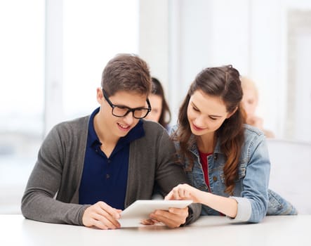 education, technology and internet - two smiling students looking at tablet pc in lecture at school