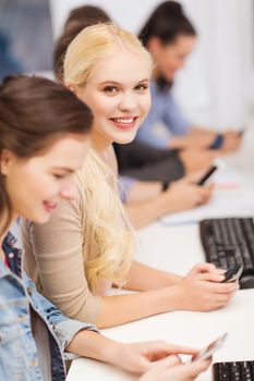 education, techology and internet concept - group of smiling students with computer monitor and smartphones