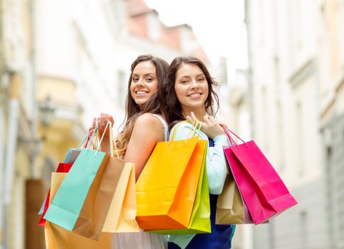 sale, shopping, tourism and happy people concept - two beautiful women with shopping bags in the ctiy