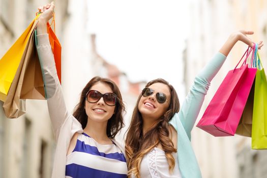 shopping, sale, happy people and tourism concept - smiling girls in sunglasses with shopping bags in ctiy