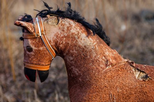 Close-up of the old threadbare rocking horse thrown away to the dump in the field