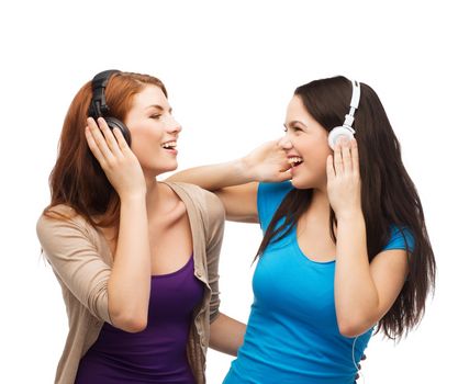 music and technology concept - two laughing teenagers with headphones