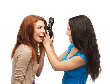 music and technology concept - two laughing teenagers sharing headphones