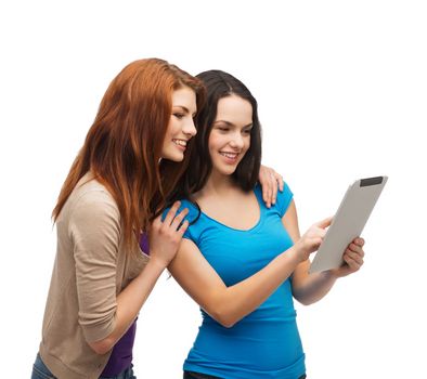 technology, friendship and people concept - two smiling teenagers pointing finger at tablet pc screen