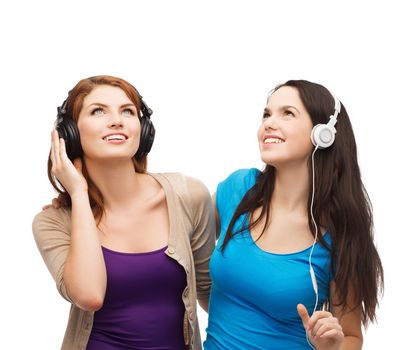 music and technology concept - two smiling teenagers with headphones looking up