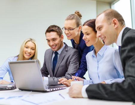 business, technology and office concept - smiling business team with laptop computers, documents and coffee having discussion in office