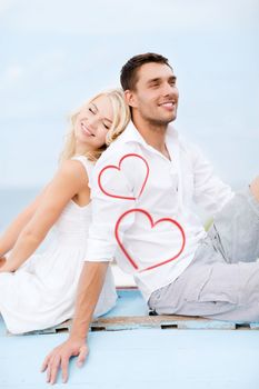 summer holidays and dating concept - couple sitting on boat at sea side