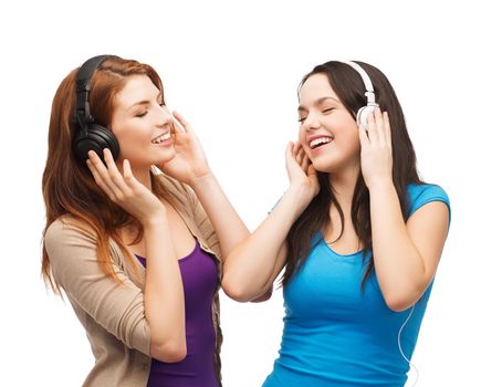 music and technology concept - two smiling teenagers with closed eyes listeting to music with headphones