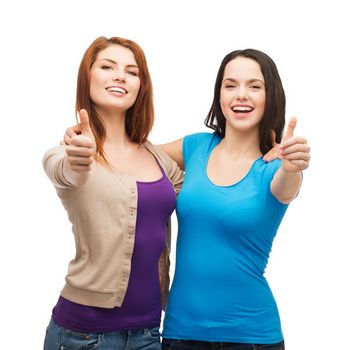 friendship and happy people concept - two smiling girls showing thumbs up