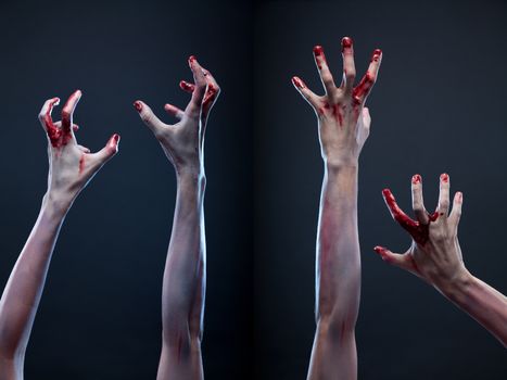 Creepy set of bloody zombie hands, studio shot over gray background  