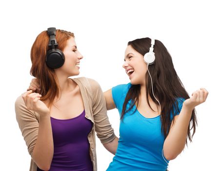 music and technology concept - two laughing teenagers with headphones