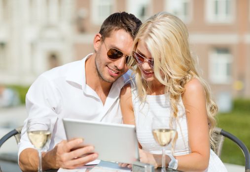 summer holidays, dating and technology concept - couple looking at tablet pc in cafe in the city