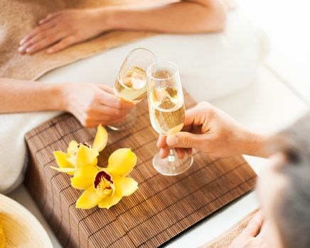 spa, health, resort, holidays and beauty concept - closeup og woman and man hands with champagne glasses