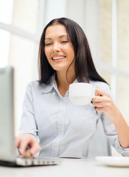 education, business and technology concept - smiling businesswoman or student with laptop computer and coffee