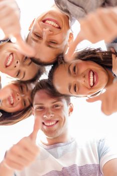 summer holidays and teenage concept - group of smiling teenagers looking down and showing thumbs up