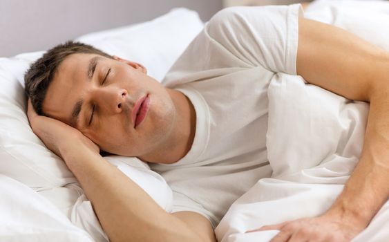 hotel, travel and happiness concept - handsome man sleeping in bed