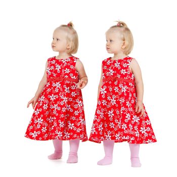 children and twins concept - two identical twin girls in red dresses looking somewhere