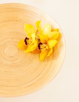 spa, health and beauty concept - closeup of wooden bowl with orchid flowers