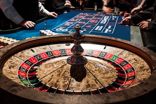 Wooden Shiny Roulette Details in a Casino with Blurry People and Croupier in Background