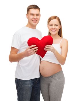 pregnancy, parenthood, love and happiness concept - happy young family expecting child with big red heart