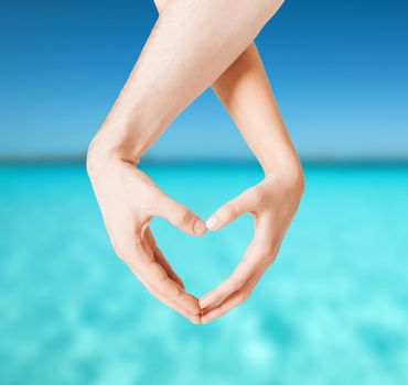 love, summer holidays and vacation concept - close up of woman and man hands showing heart shape